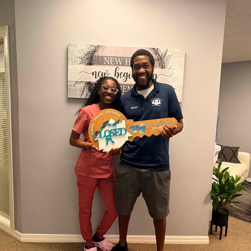 Happy buyers holding a giant Closed key on closing day